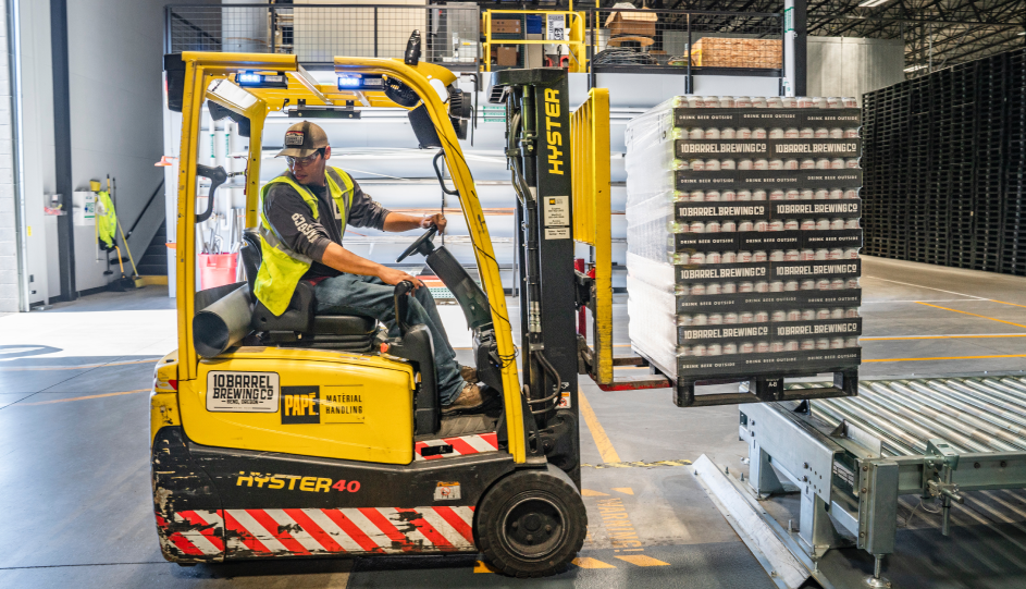 a warehouse worker drives a forklift truck